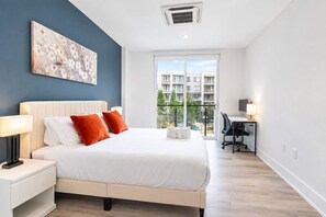 A hotel room with a bed, a desk, a chair, and a view of the outside. - Fresh 1BD Near City Hall | Comfortably Sleeps 2 (Philadelphia)