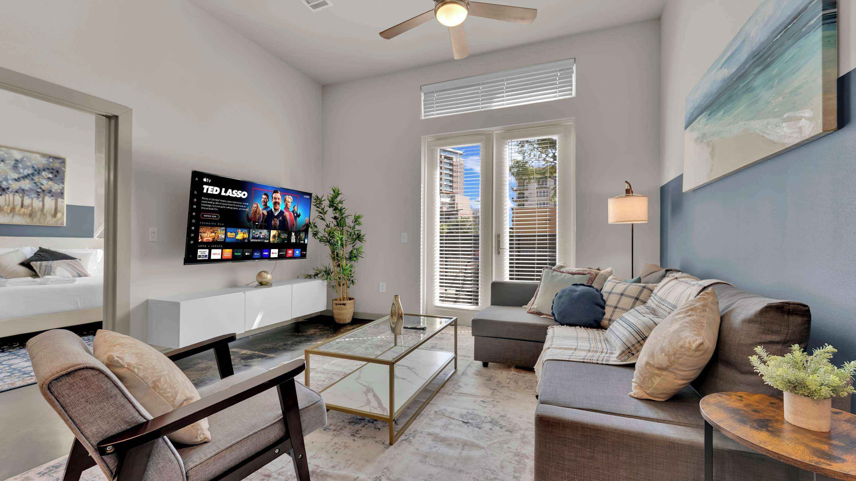 A modern living room with a flat-screen TV, a sofa, a coffee table, and a chair.
