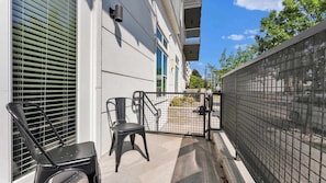A balcony with a chair, a gate, and a building facade. - Uptown 1BR | Sleeps 4 | Near Klyde Park (Dallas)