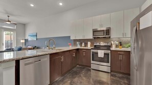 A modern kitchen with a dishwasher, stainless steel appliances, and a granite countertop. - Uptown 1BR | Sleeps 4 | Near Klyde Park (Dallas)