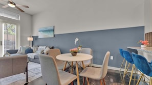 A modern living room with a sofa, a round dining table, and chairs. - Uptown 1BR | Sleeps 4 | Near Klyde Park (Dallas)