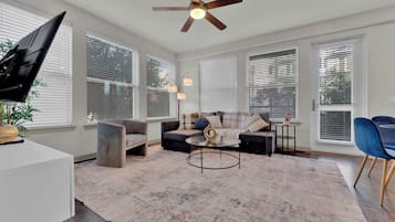 A living room with a ceiling fan, a sofa set, a coffee table, and a TV.
