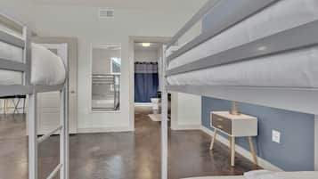 A hotel room with bunk beds, a small desk, and a bathroom visible through an open door.