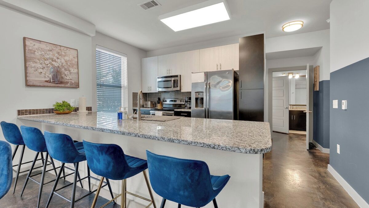 A modern kitchen with a central island, bar stools, and stainless steel appliances.