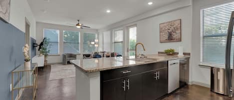 A modern kitchen with a central island, dark cabinetry, and a dining area with a sofa and chairs.