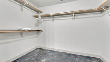 A room with a concrete floor, white walls, and three wooden beams with metal brackets.