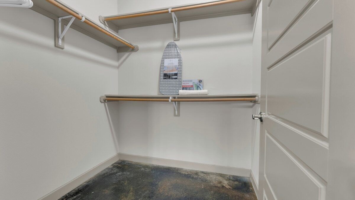 A room with a built-in ironing board, a shelf with a box, and a door.