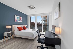 A modern bedroom with a bed, bedside tables, a desk, and a chair. - Contemporary 1BR | Sleeps 2 | Northern Liberties (Philadelphia)
