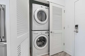 A laundry room with two stacked washing machines and a closed door. - Contemporary 1BR | Sleeps 2 | Northern Liberties (Philadelphia)