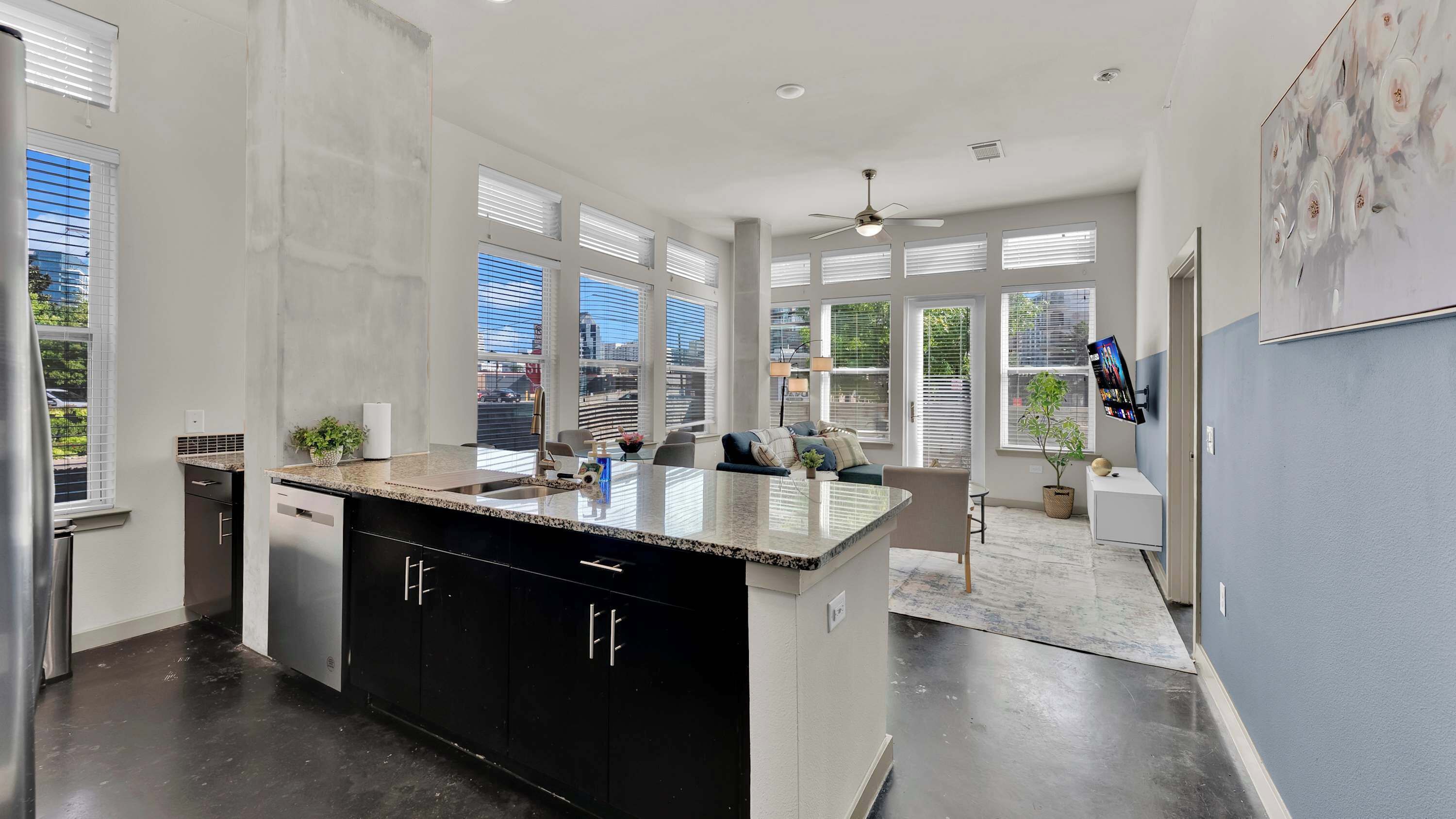 A modern kitchen with a large island, built-in appliances, and large windows offering city views.