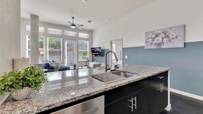 A modern kitchen with granite countertops, a stainless steel sink, and black cabinetry. - Luxury 2BR Uptown | Sleeps 12 | Parking (Dallas)