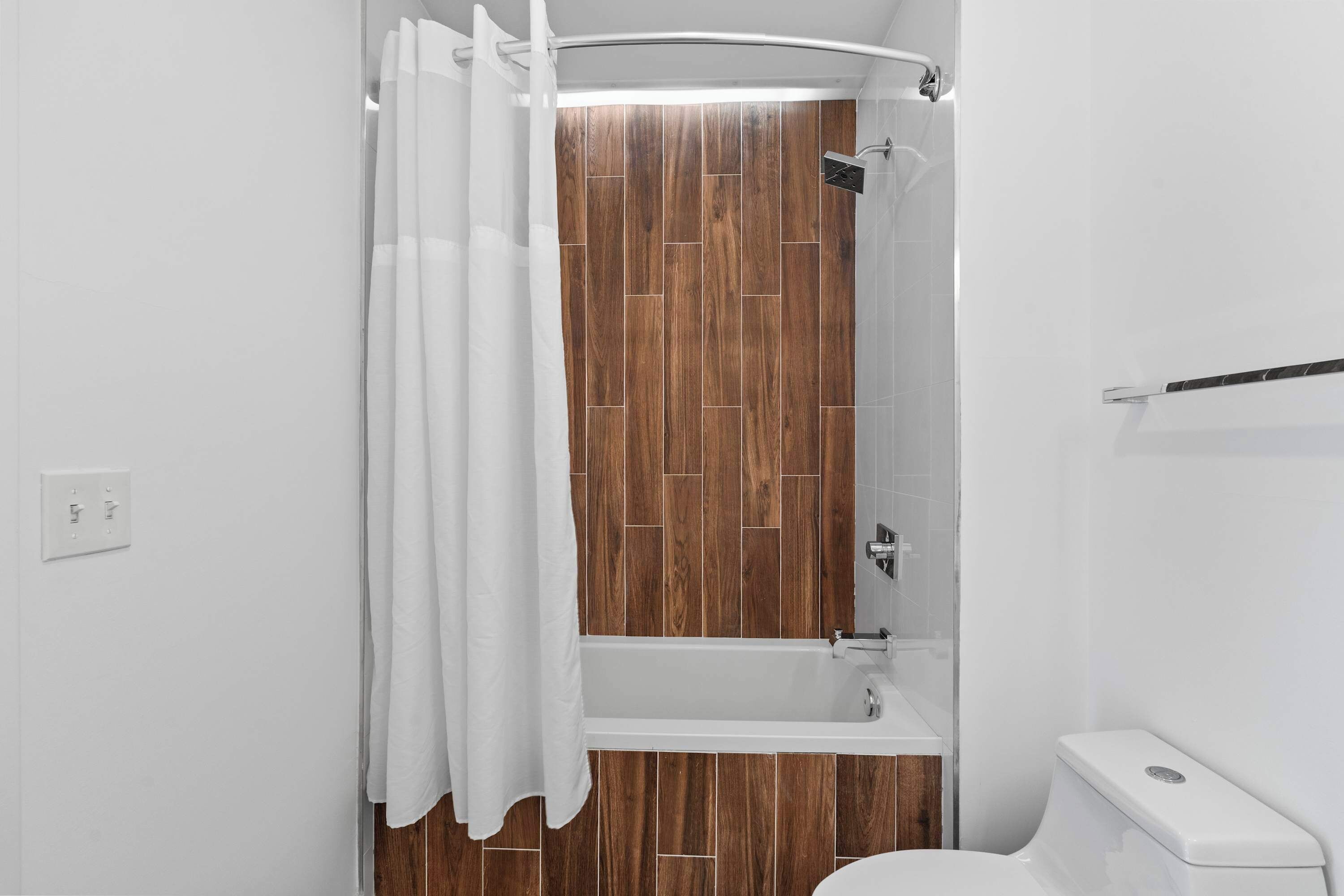 Un bagno con pavimento in legno, una vasca, un water e una doccia.