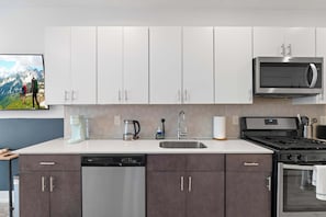 A modern kitchen with white and dark cabinets, stainless steel appliances, and a dishwasher. - Spacious 3BR | Sleeps 8 | Northern Liberties (Philadelphia)