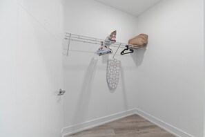 A corner of a room with a white wall, a metal rack with clothes, and a patterned item hanging. - Spacious 3BR | Sleeps 8 | Northern Liberties (Philadelphia)