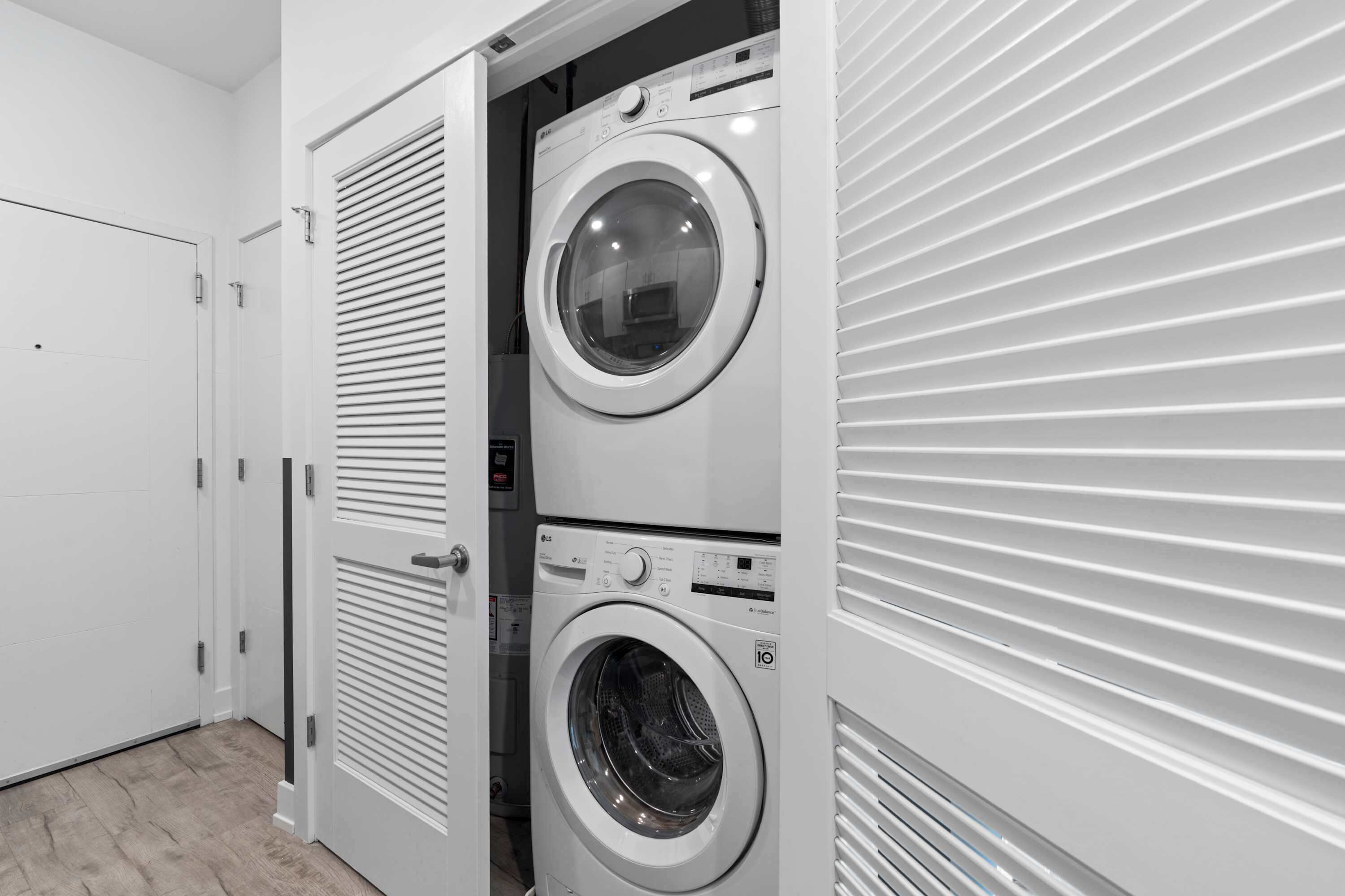 A laundry room with two stacked washing machines and a closed door.