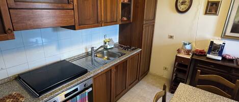 A kitchen with wooden cabinets, a stove, a sink, and a dining table with chairs.