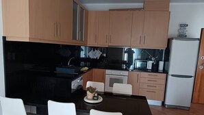 A modern kitchen with wooden cabinets, a black countertop, and a white dining table with chairs.