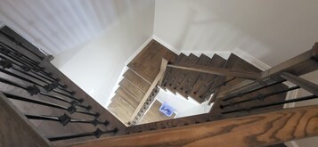 Eine Holztreppe mit Handlauf und Blick auf einen Raum darunter.