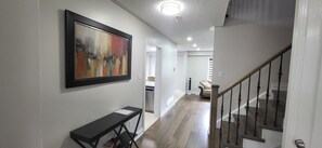 A hallway with a staircase, a framed abstract painting, and a console table.