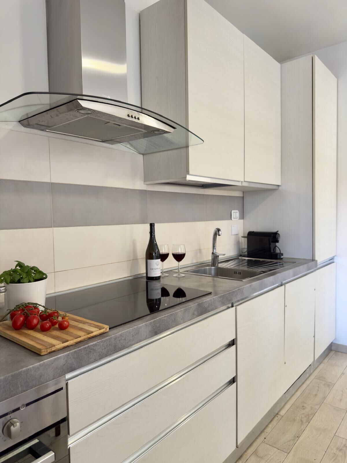 Een moderne keuken met roestvrijstalen apparatuur, een ingebouwde oven en een wijnfles op het aanrecht.