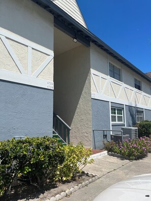 A building with a beige facade, numbered windows, and a clear blue sky. - The Pioneer Cottage - 1BR Near Disney & Airport (St. Cloud)