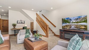 Una sala de estar con escalera, chimenea, televisor y un ventanal grande.