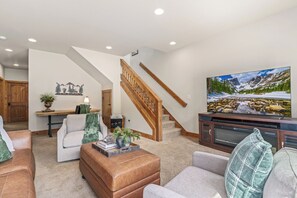 Ein Wohnzimmer mit Treppe, Kamin, Fernseher und einem großen Fenster.