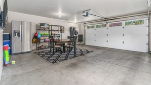 Un garaje con una mesa de comedor, sillas y un refrigerador.