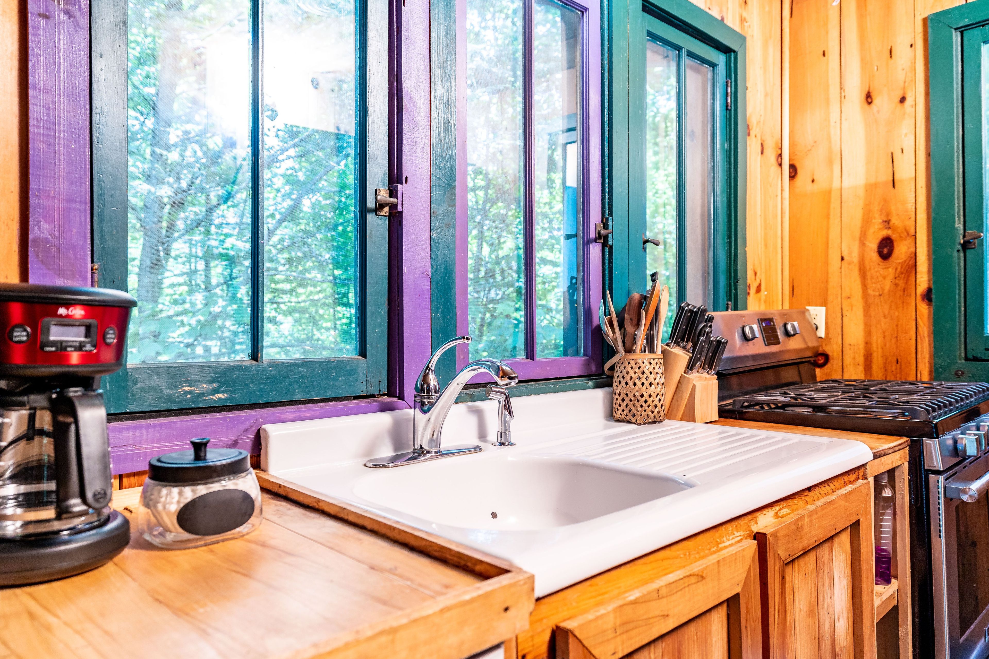 A kitchen with a white sink, stainless steel stove, and wooden cabinets.