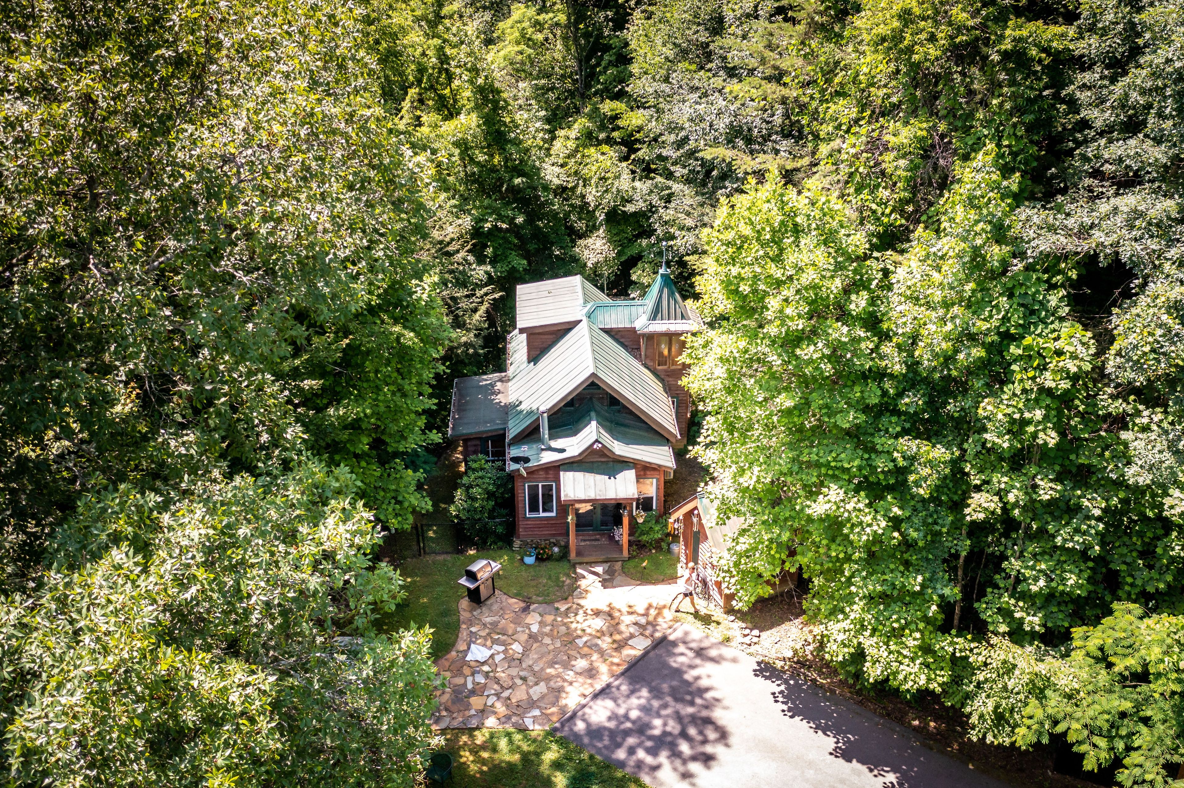 A wooden cabin surrounded by dense forest, with a stone pathway leading to the entrance.