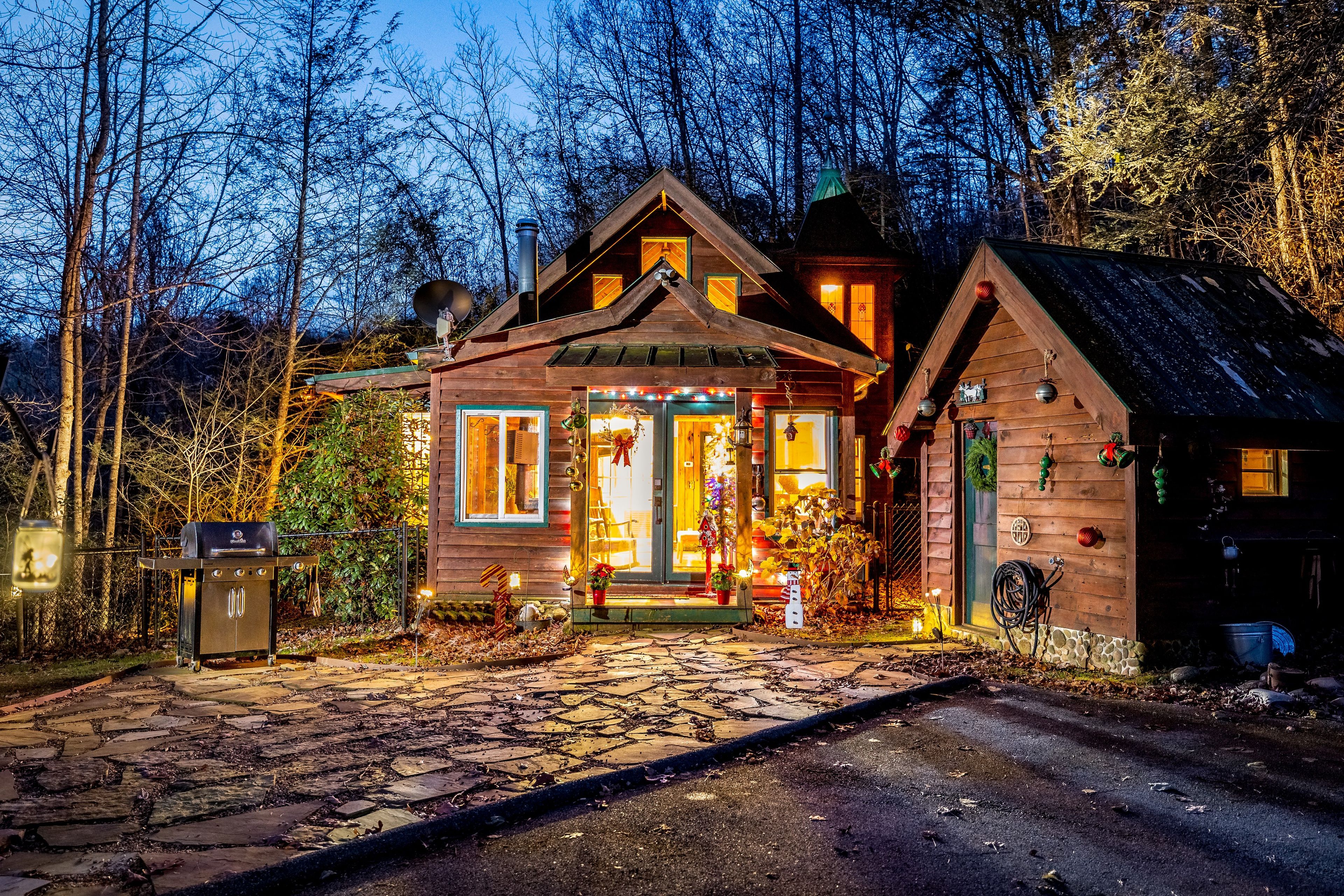 Une cabane en bois avec un porche, une antenne parabolique et un chemin de pierre menant à l’entrée.