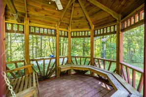 A wooden gazebo with a curved bench, surrounded by a wooden railing, and a view of a forested area. - Storybook in the Smokies - Secluded, Free Pet, Hot Tub, BBQ, Washer & Dryer (Pigeon Forge)