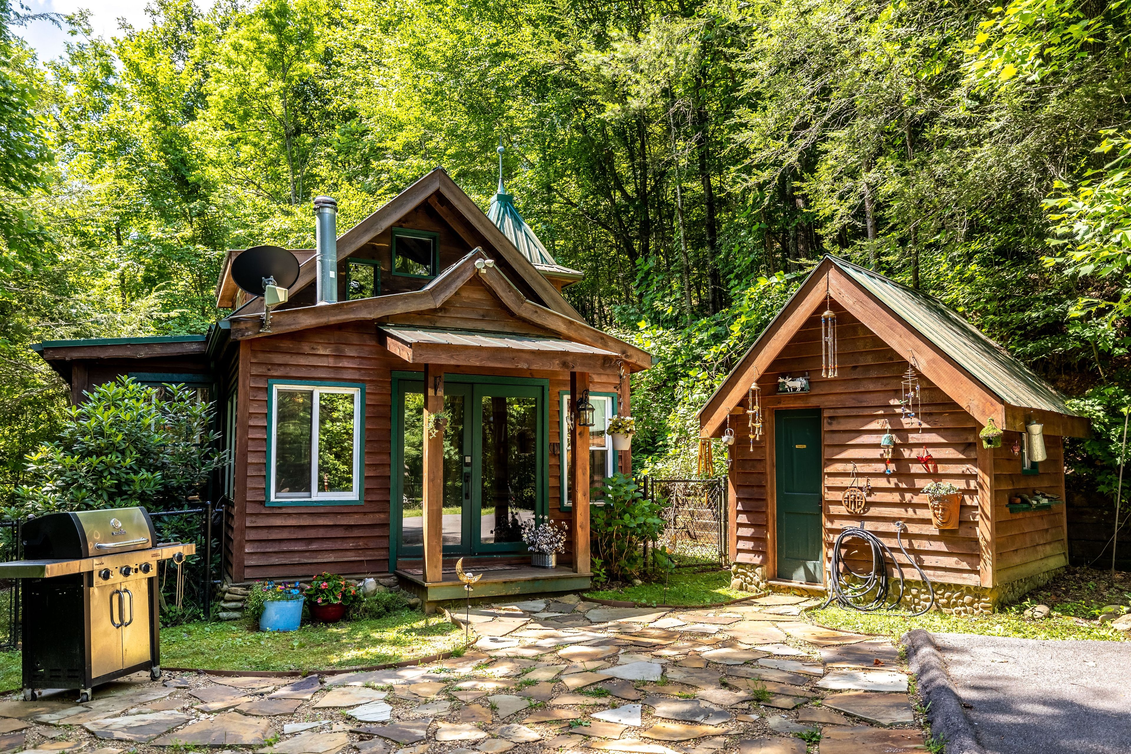 A wooden cabin with a chimney, a small porch, and a stone pathway leading to it.