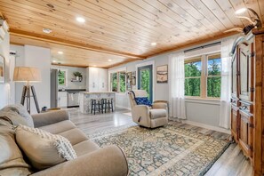 A spacious living room with a sofa, a recliner, a patterned rug, and a wooden ceiling. - 3BR Cabin – 3 Min to Flagstaff Lake, 23 Min to Sugarloaf – Pet Friendly. (Eustis)