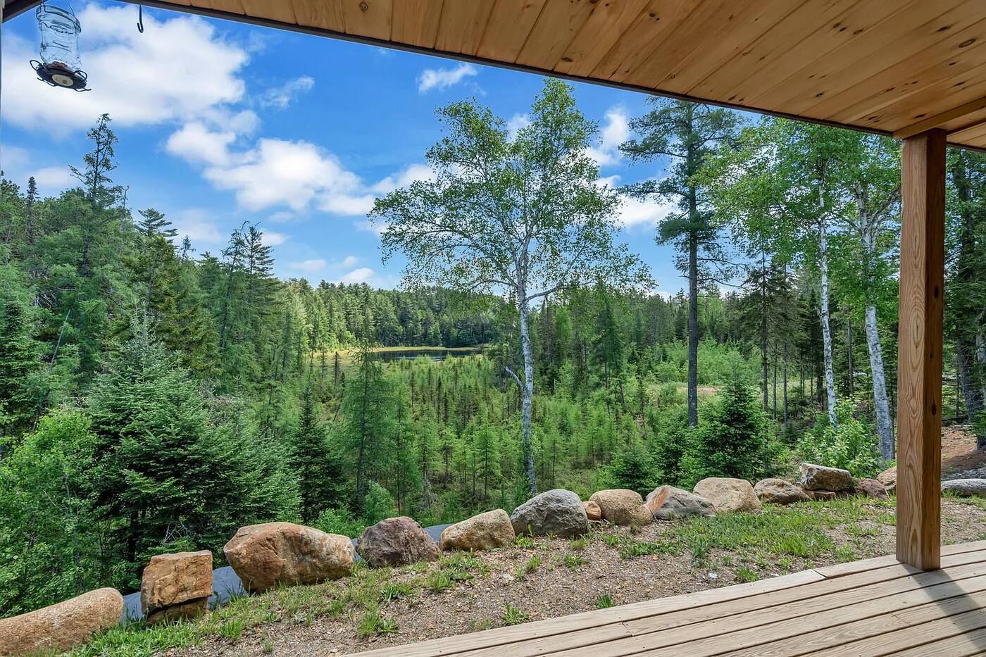 Eine Holzterrasse mit Blick auf eine bewaldete Landschaft und einen klaren Himmel.