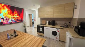 Ett modernt kök med träskåp, diskmaskin, tvättmaskin och kaffebryggare.