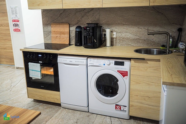 A compact kitchen with a built-in oven, dishwasher, and washing machine.