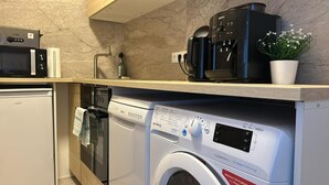 Eine kleine Küche mit Mikrowelle, Kaffeemaschine und Waschmaschine.