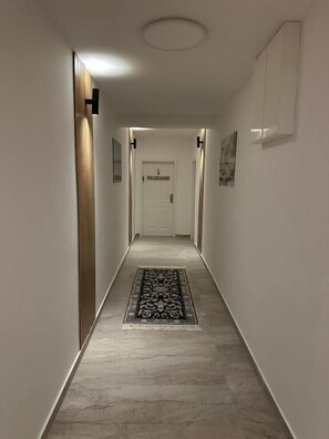 A narrow hallway with a patterned rug, a door at the end, and a light fixture on the ceiling. - Ferienwohnung im Bramfelder 3 (Wandsbek-Hamburg)