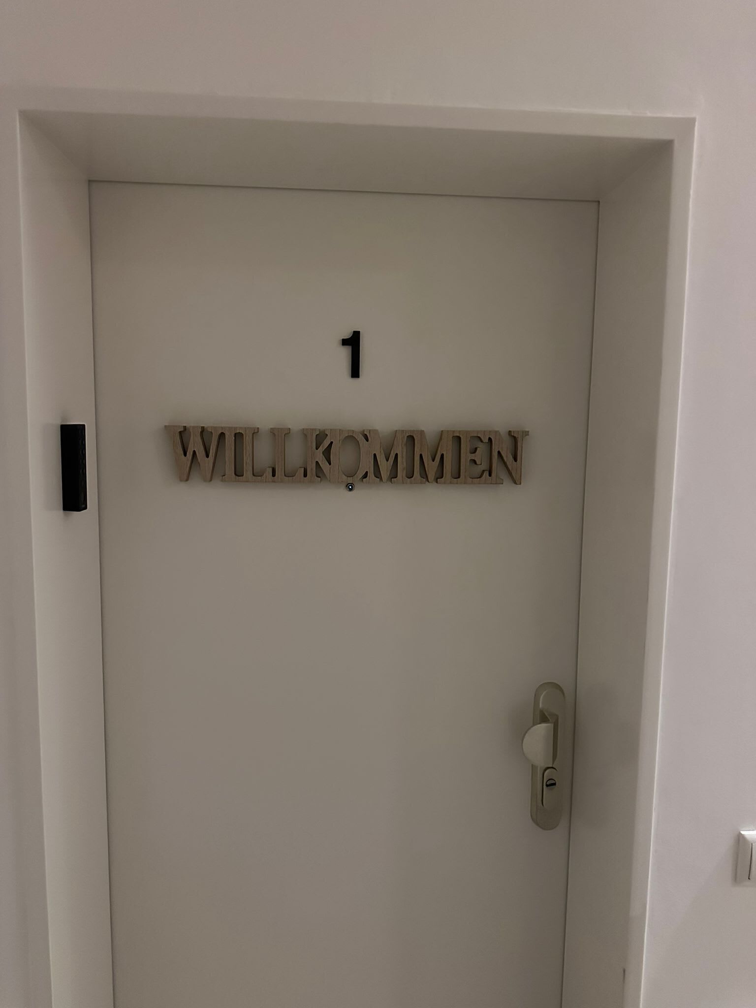 Eine Tür mit der Nummer 1 und dem Schriftzug 'WILLKOMMEN', ein Willkommensschild.