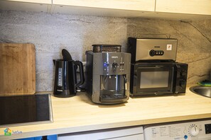 Une cuisine équipée d’une machine à café, d’un four à micro-ondes et d’un grille-pain, le tout posé sur le plan de travail.
