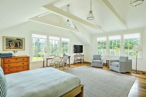 A spacious bedroom with a large bed, a desk, two chairs, a television, and a painting on the wall. - Cozy, renovated 1-bedroom studio in Westport Point with AC (Westport)