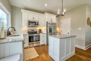 A kitchen with white cabinetry, stainless steel appliances, granite countertops, and a central island. - Modern 2-bedroom house with AC in delightful Muscle Shoals (Muscle Shoals)