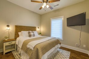A bedroom with a bed, nightstands, a ceiling fan, a TV, and a window with blinds. - Modern 2-bedroom house with AC in delightful Muscle Shoals (Muscle Shoals)