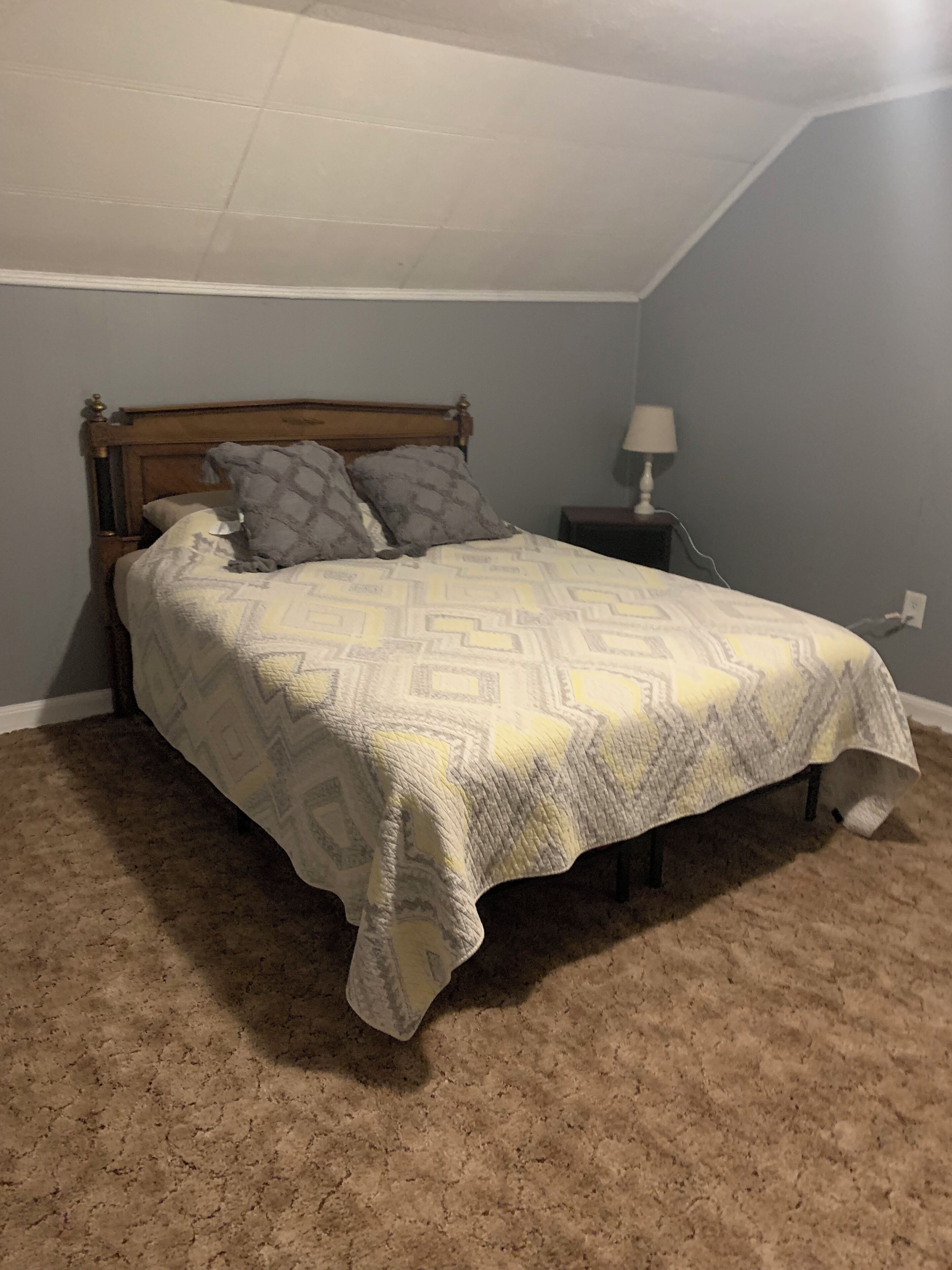 A bedroom with a bed, a nightstand, and a lamp.