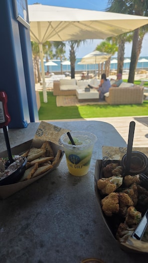 Une table avec une boisson, un panier de produits frits et une boîte de nourriture.