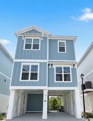 A two-story building with a garage entrance and a covered driveway. - SEACHELES Orange Beach BIG FALL Savings.  3 brd 5 beds 4 Baths SLEEPS 10 (Orange Beach)