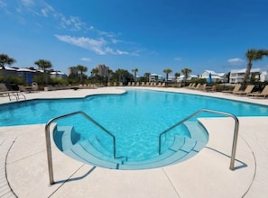 Une piscine à bord incurvé, entourée de chaises longues et de palmiers.