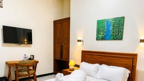 A hotel room with a wooden bed, a flat-screen TV, a desk, and a painting on the wall.