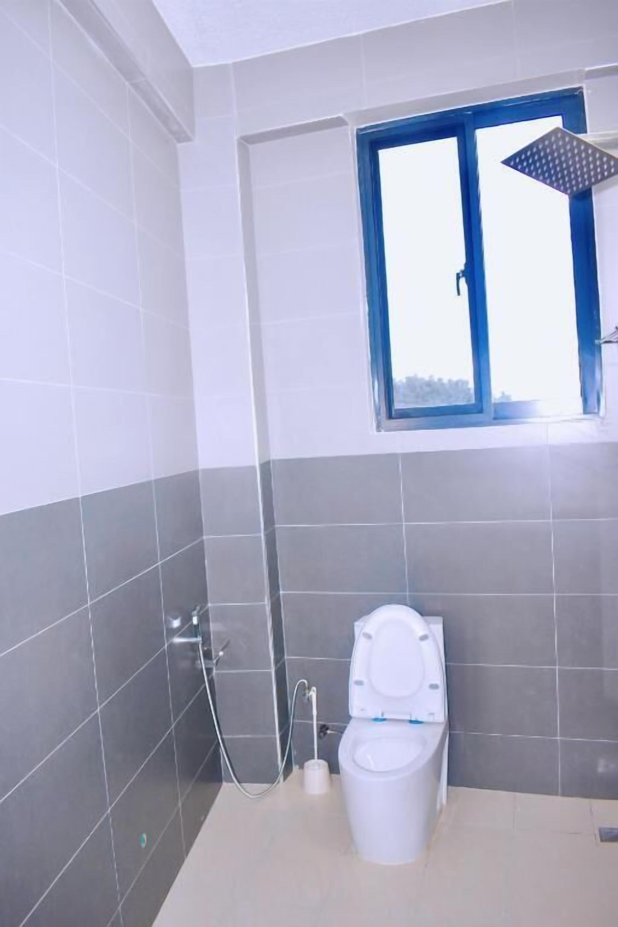 Une salle de bain avec des toilettes, une douche et une fenêtre.